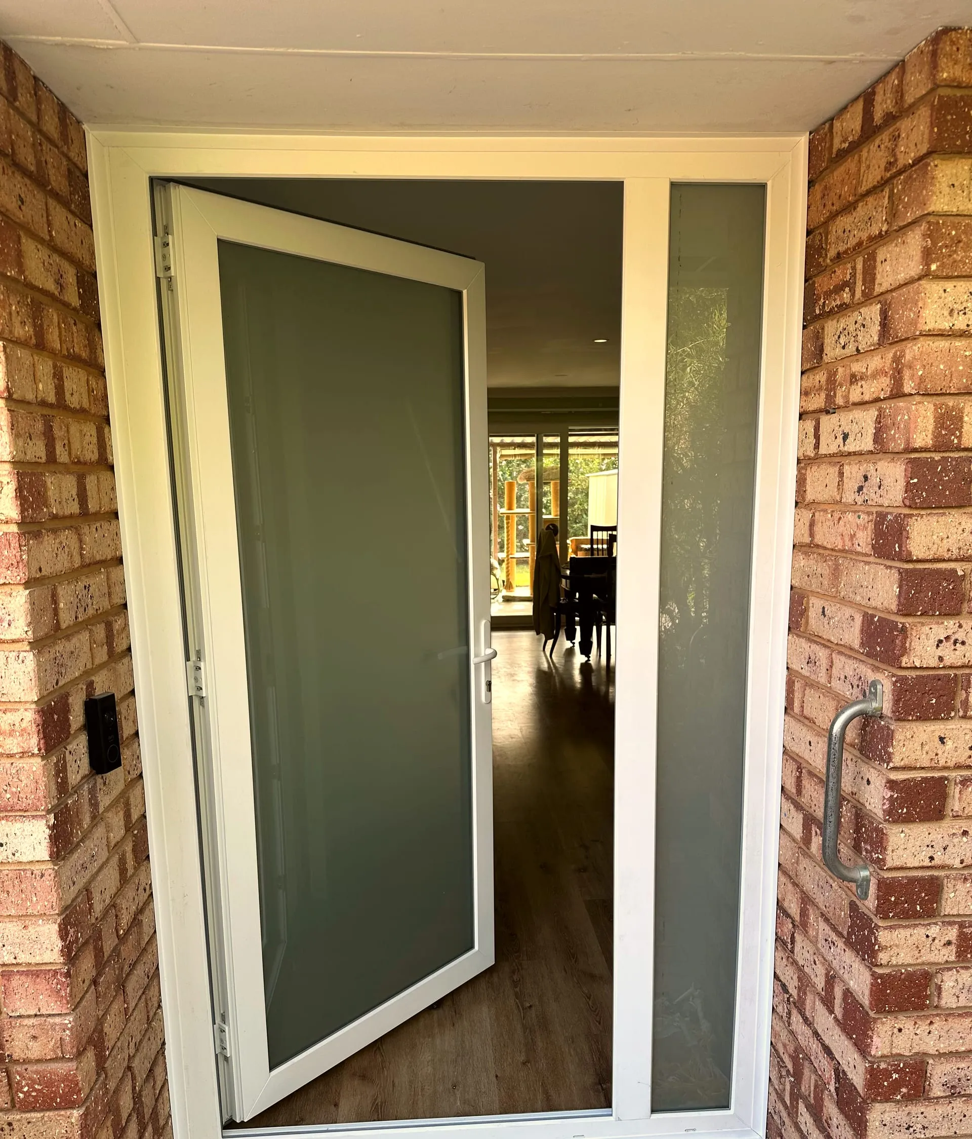 White uPVC entrance door with obscure glazing and a matching glazed sidelight, standing open in a brick reveal — GaBe Double Glazing install, Perth