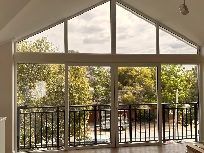 Full-height balcony doors with a black balustrade under a raked ceiling
