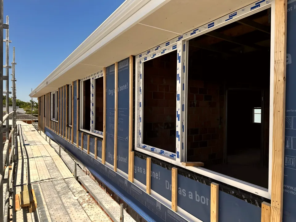 uPVC windows fitted to a new build still wrapped in building membrane, scaffold in place