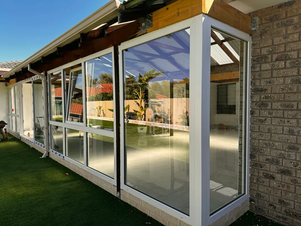 White-framed glass patio enclosure on lawn