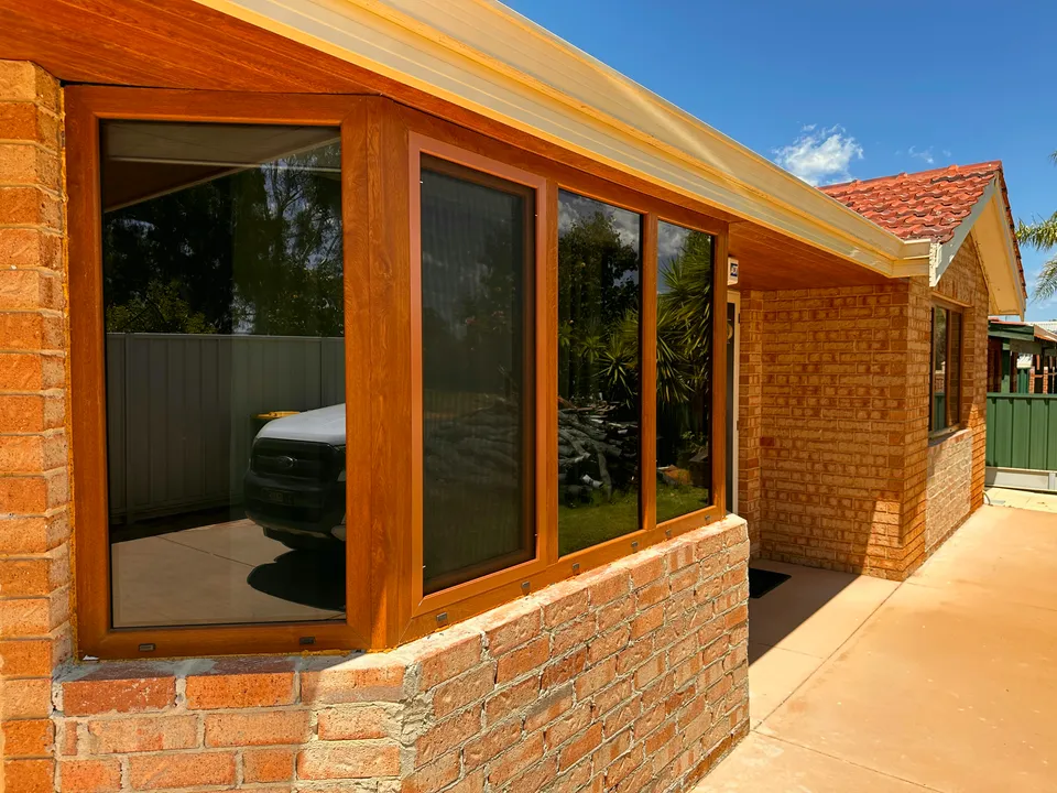 Golden-oak double-glazed retrofit windows on cream-brick home