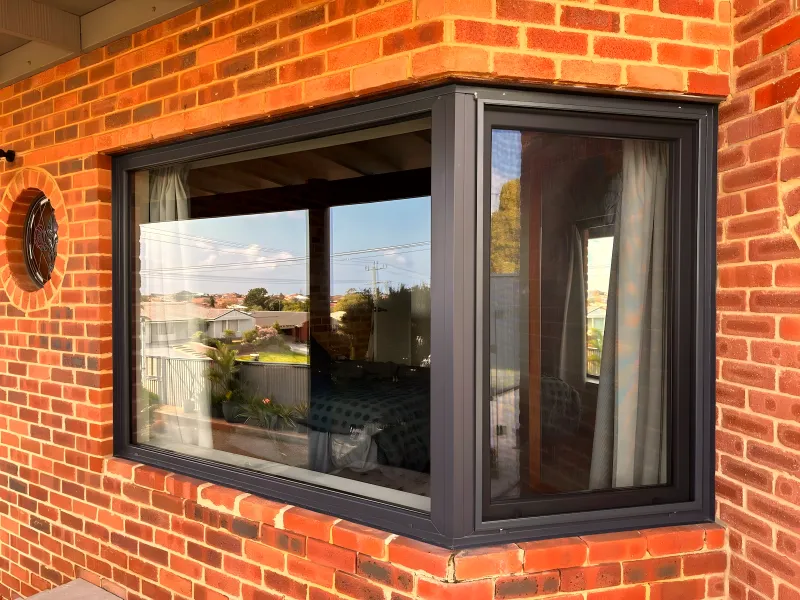 Anthracite retrofit corner window in red brick