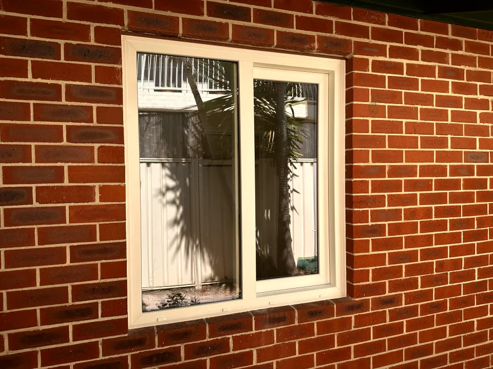 Cream uPVC sliding window in red-brick wall