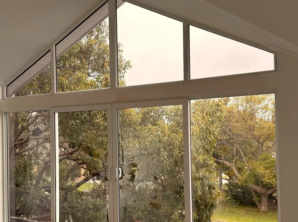 Pitched gable window and sliding glass door in a Perth home, framing a leafy outlook