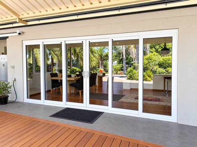 Luxury white uPVC stacker door opening a bright kitchen and dining area to the alfresco