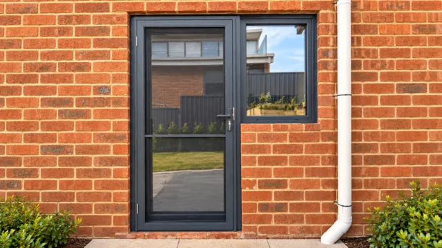 Anthracite glazed laundry door beside a matching window in a brick wall