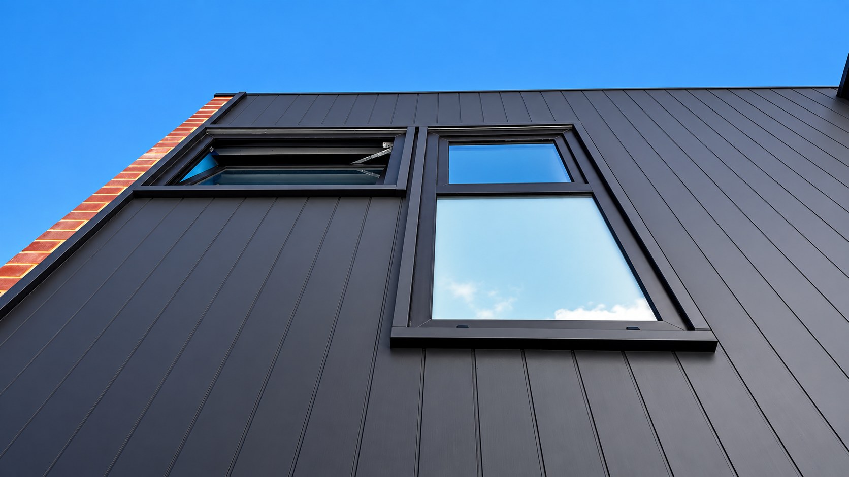 Modern charcoal-clad exterior with a sleek uPVC window set against a blue sky
